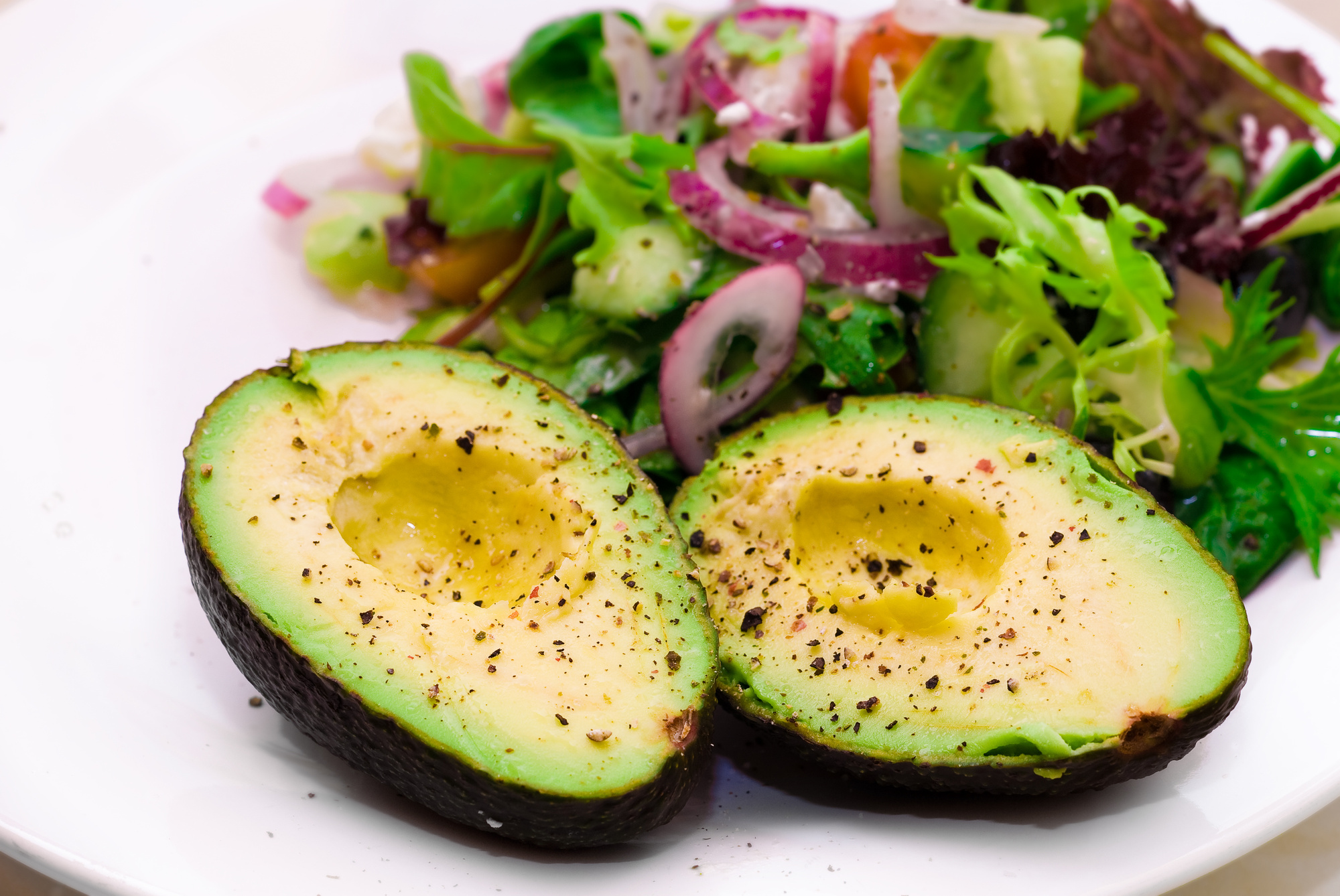 Avacado halves, seasoned with side-salad.